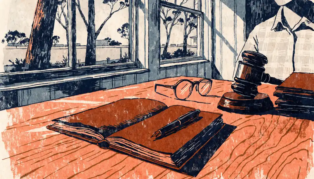 Sunlit home office desk with notebook, glasses and gavel near a window